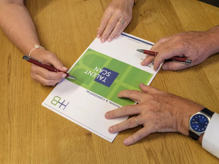 Handen met het Talent Scan-boekje van HB op tafel
